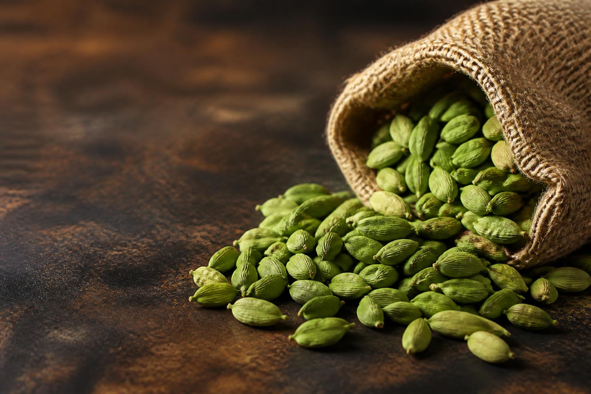 Bright green cardamom pods spilling from a jute export sack